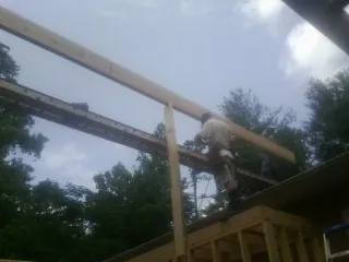Carpenter setting a ridge beam over a new addition frame — Ice Dam Removal by Roofing Brothers in Preemption
