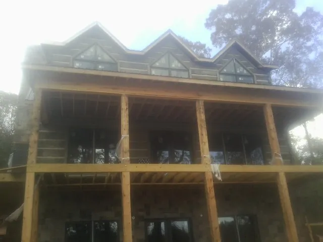 Dormers and porch framing on a large log home under construction — Roof Coating work by our crew in Preemption