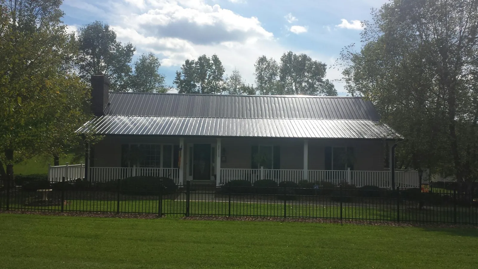 Gray metal roof on a brick ranch with a full width front porch — Gutter Guard Installation work by our crew in Preemption