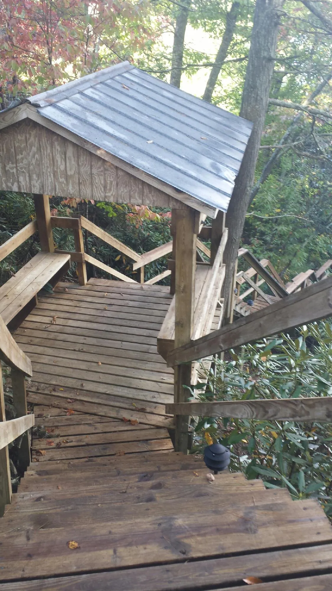 Metal roofed shelter over wooden steps on a wooded walkway — Skylight Repair & Installation work by our crew in Preemption