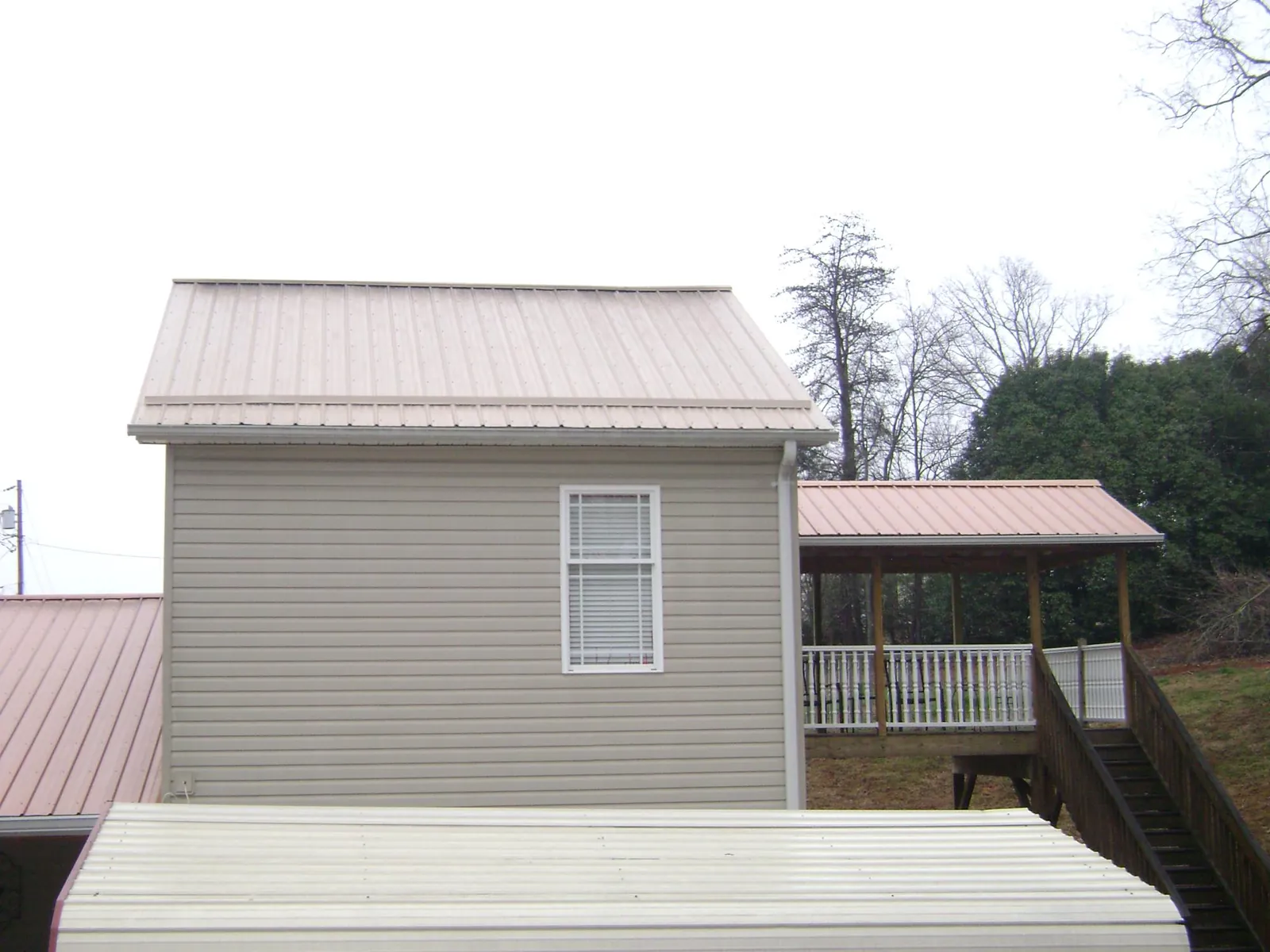 Tan metal roofs on a two story addition and attached porch, from a Roof Replacement job in Preemption