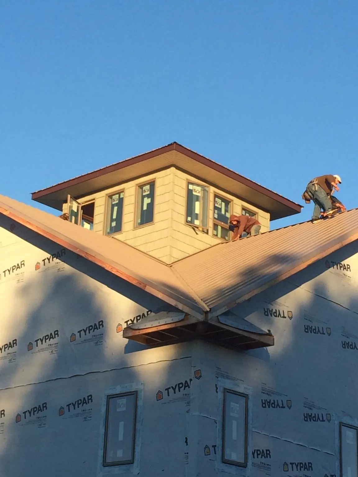 Roofers working around a rooftop cupola on a new metal roof at sunset — Roof Waterproofing in Preemption by Roofing Brothers